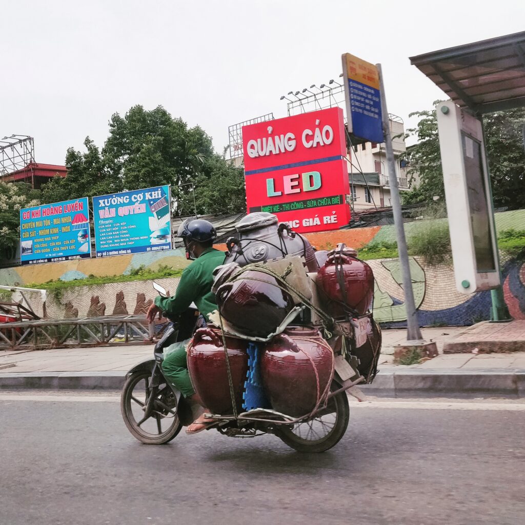 Motor cyclist in Hanoi carrying a lot of goods